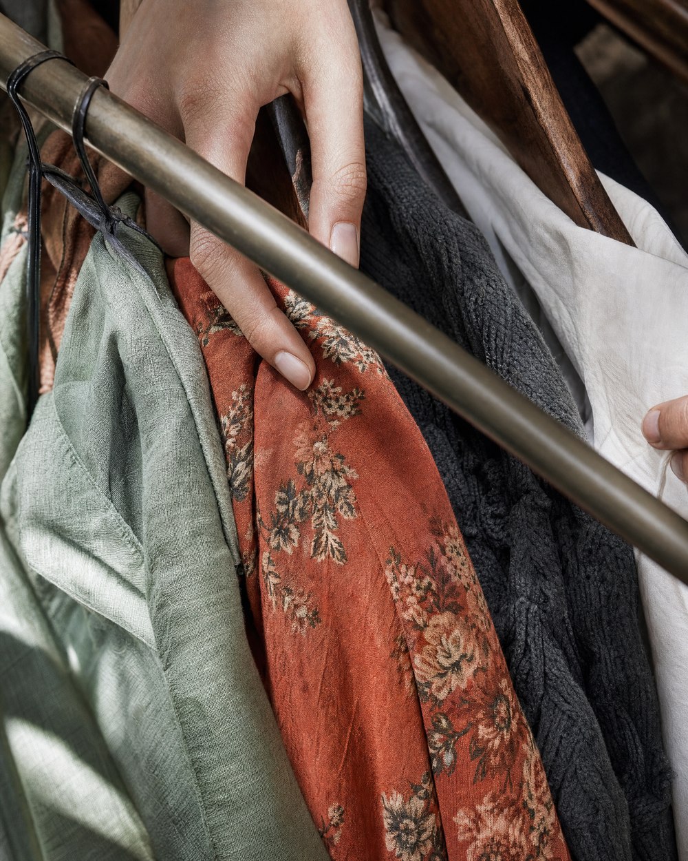 Hands going through a rack of jackets and dresses
